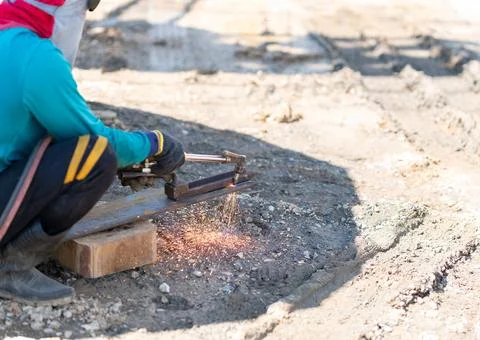 Construction worker using an oxy-fuel cutting torch to cut a heavy steel be.. Stock Photos