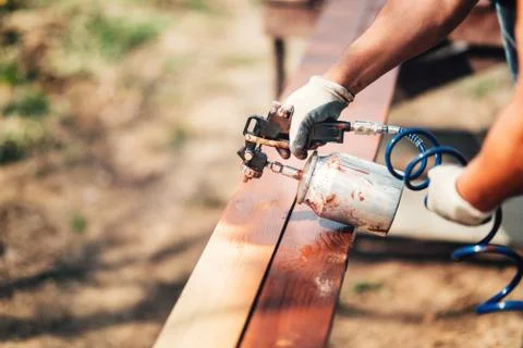 Construction worker using paint gun and brown paint during renovation works.  Stock Photos