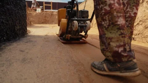 Construction worker using plate compactor on sand Stock Footage 341294825