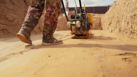 Construction worker using plate compactor on sand Stock Footage 341294840