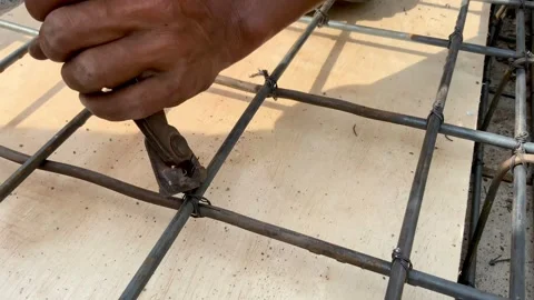 Construction worker using pliers to tie steel rebar grid for concrete reinforcem Видео 334533354