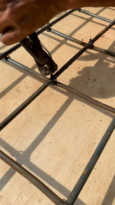 Construction worker using pliers to tie steel rebar grid for concrete reinforcem Видео 334533814