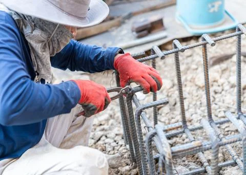 A construction worker using pliers to tie rebar steel wire. Stock Photos