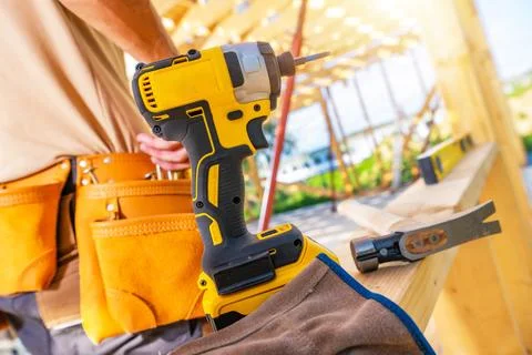 Construction Worker Using a Power Drill at a Building Site During Daylight .. Stock Photos