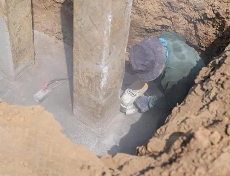 Construction worker using a power grinder to cut into a concrete foundation.. Stock Photos