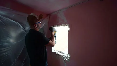 Construction worker using a power saw to cut a hole in a wall for a window Stockbeeldmateriaal 347640519