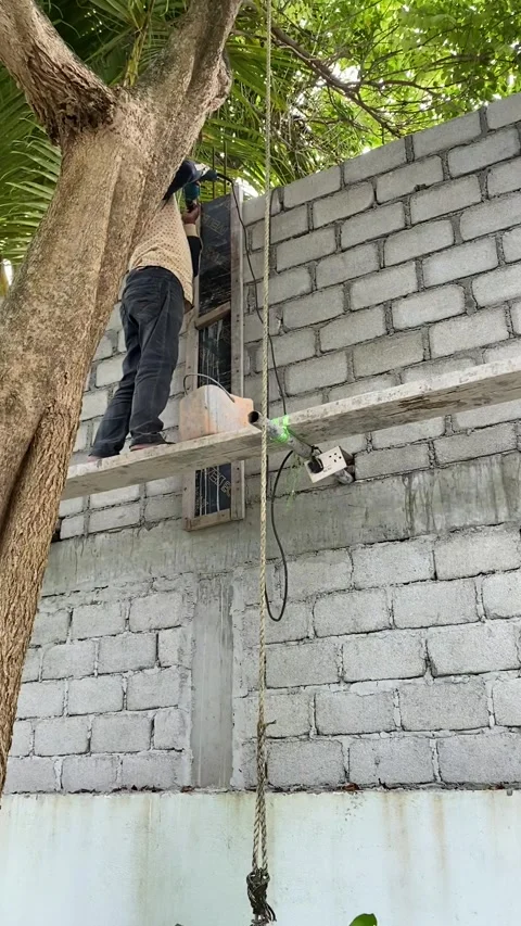 Construction worker using power tool on building wall Maldives vertical Stock Footage 344699671