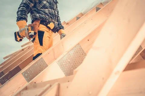 Construction Worker Using Power Tool on Roof During Daylight at a Building .. Stock Photos