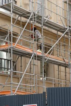 Construction worker using power tools to work on building facade while on s.. Stock Photos