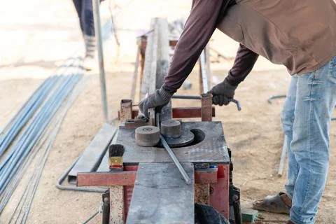 Construction worker using a rebar bending machine to shape steel reinforcem.. Stock Photos