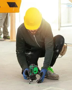 Construction worker using rotating laser level on tripod at construction site Stock Photos