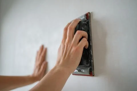 Construction worker is using a sanding block to smooth a wall during a home Stock Photos