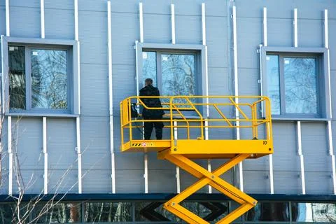 Construction worker using a scissor lift to install building cladding crate Stock Photos