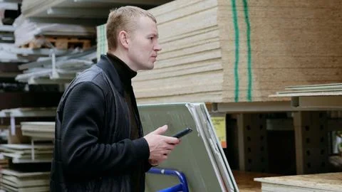 Construction worker using a smartphone to browse materials and prices in a Stock Photos