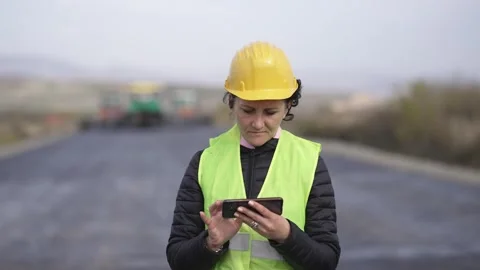 Construction worker using smartphone during a road project at a worksite Stock Footage 304353073