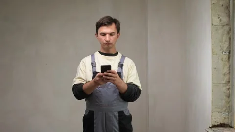 Construction worker using smartphone in unfinished room Stock Footage 313299735