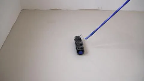 Construction worker using a spiked roller to level the floor. Stock Photos