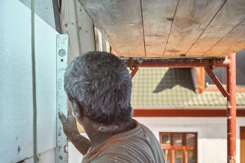 Construction worker using spirit level to measure foam insulation installed.. Stock Photos