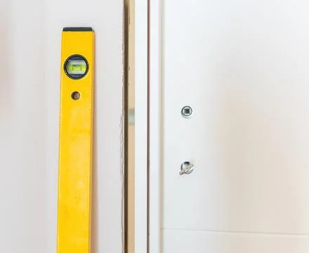 Construction worker using spirit level installing white door in a house Stock Photos