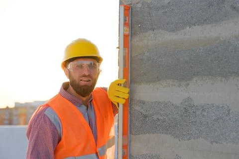 Construction worker using spirit level on building site at sunset Stock Photos
