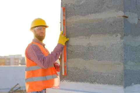 Construction worker using spirit level on building site at sunset Stock Photos