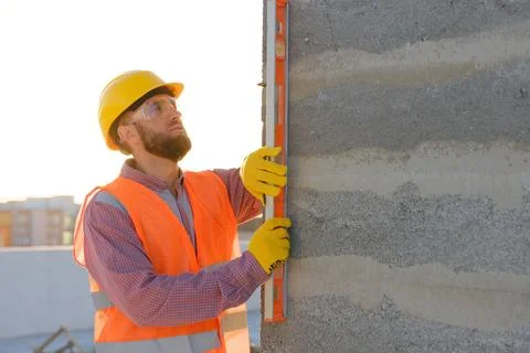 Construction worker using spirit level on building site at sunset Stock Photos