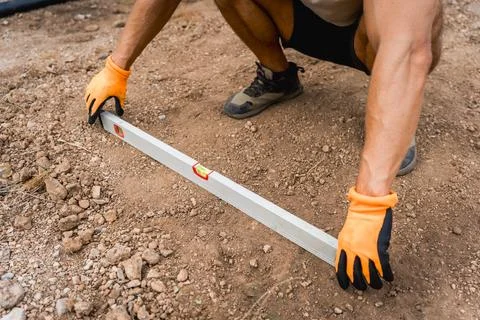 Construction worker using spirit level on site on the ground during work, close 库存照片