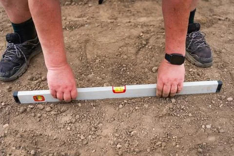 Construction worker using spirit level on site on the ground during work, close 库存照片