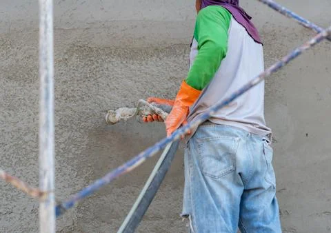 Construction worker using a spray machine hose to apply wet mortar or cemen.. Photos