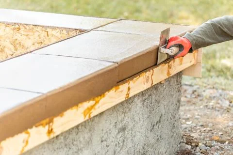 Construction Worker Using Stainless Steel Edger On Wet Cement Forming Coping  Foto stock