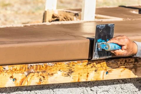 Construction Worker Using Stainless Steel Edger On Wet Cement Forming Coping  Foto stock