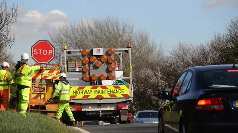 Construction worker using stop go lollipop at roadworks uk Stock Footage 88169772
