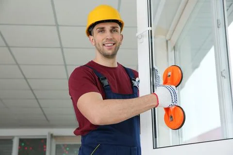 Construction worker using suction lifter during window installation indoors Stock Photos