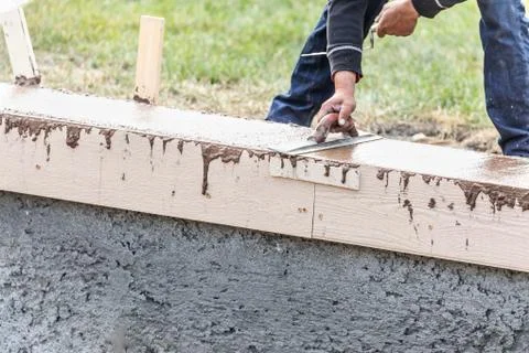 Construction Worker Using Trowel On Wet Cement Forming Coping Around New Pool Stock Photos