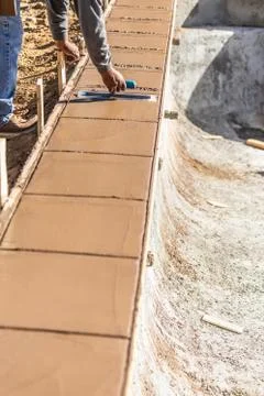 Construction Worker Using Trowel On Wet Cement Forming Coping Around New Pool Stock Photos