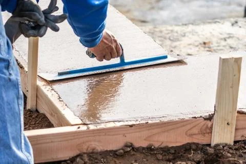 Construction Worker Using Trowel On Wet Cement Forming Coping Around New Pool Stock Photos