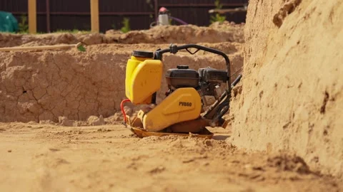 Construction worker using vibratory plate compactor on sand Stock Footage 341294866