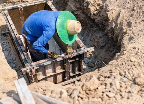 A construction worker using wire to secure steel reinforcement bars. Stock Photos