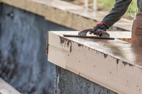 Construction Worker Using Wood Trowel On Wet Cement Forming Coping Around New Stock Photos