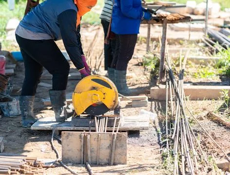 Construction worker using a yellow abrasive cut-off saw machine to slice th.. Stock Photos