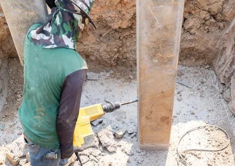 Construction worker using a yellow electric jackhammer to break concrete on.. Stock Photos