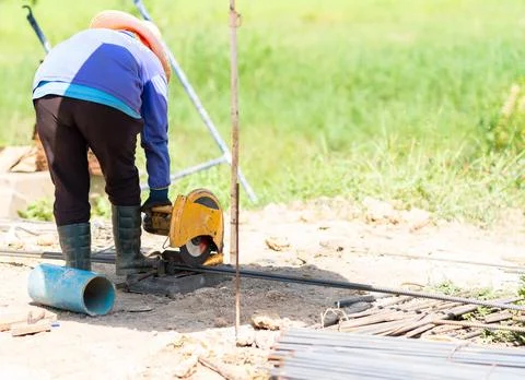 Construction worker using a yellow metal chop saw machine to cut steel reba.. Stock Photos