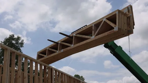 Construction worker utilizes machinery to lift wooden telehandler beams under Stock Footage 319390544