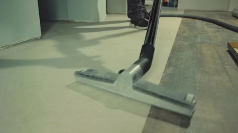 Construction worker vacuuming vinyl laminate flooring before installation Stock Footage 316389629