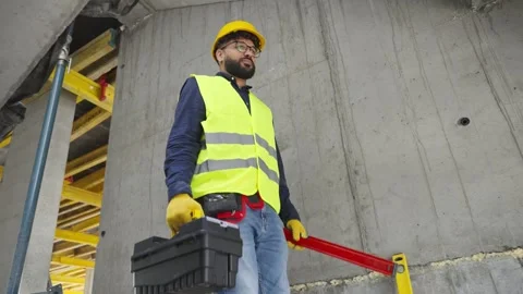 Construction worker walking on building site with toolbox Stock Footage 343450365