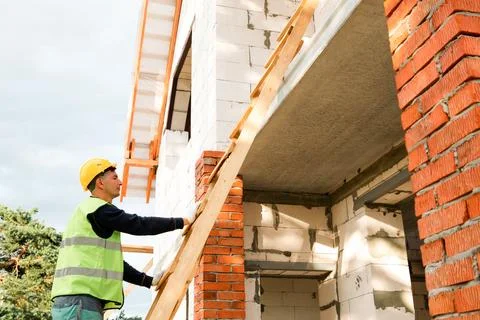 Construction worker at wall, checks alignment, starts building process, mea.. Stock Photos