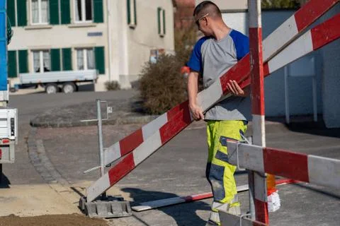 Construction worker with warning clothes is holding barriers of a construction. Stock-Fotos