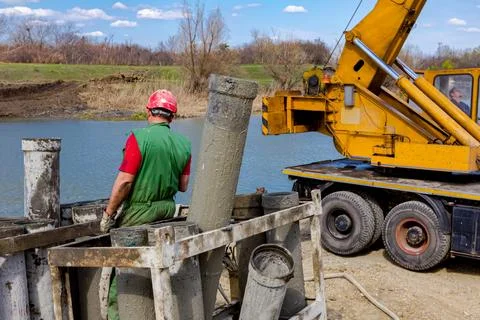 Construction worker washing separated metal pump tube, canal of fresh concret Stock Photos