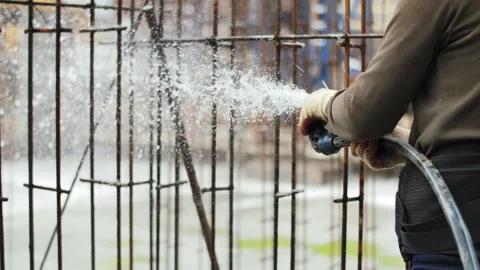 Construction worker watering concrete foundation for curing Stock Footage 311593136