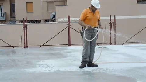 Construction worker watering fresh concrete slab using a hose. Video stock 248428759